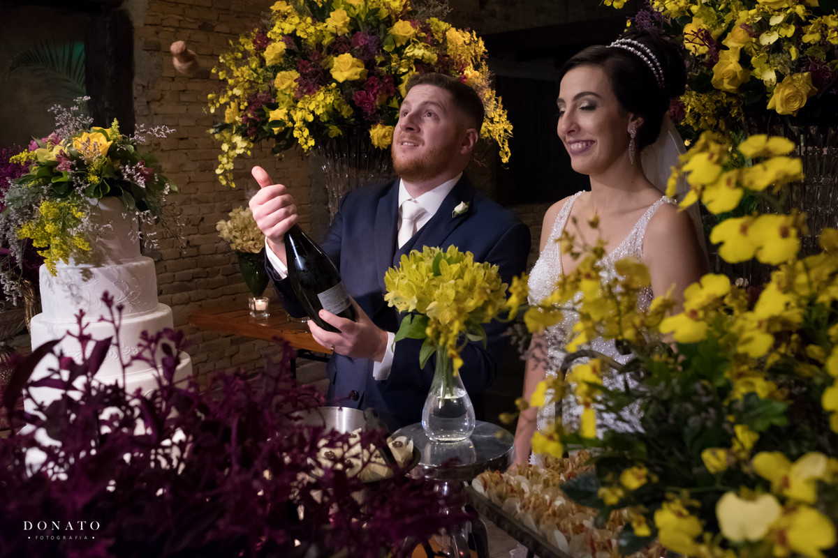 Noivo estoura a janpagne na mesa do bolo.