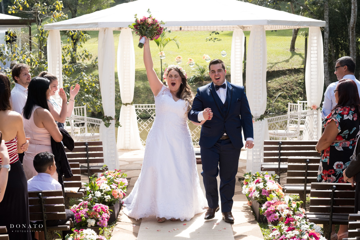 Noiva e noivo saem da cerimonia do espaço natureza em um lindo dia de sol.