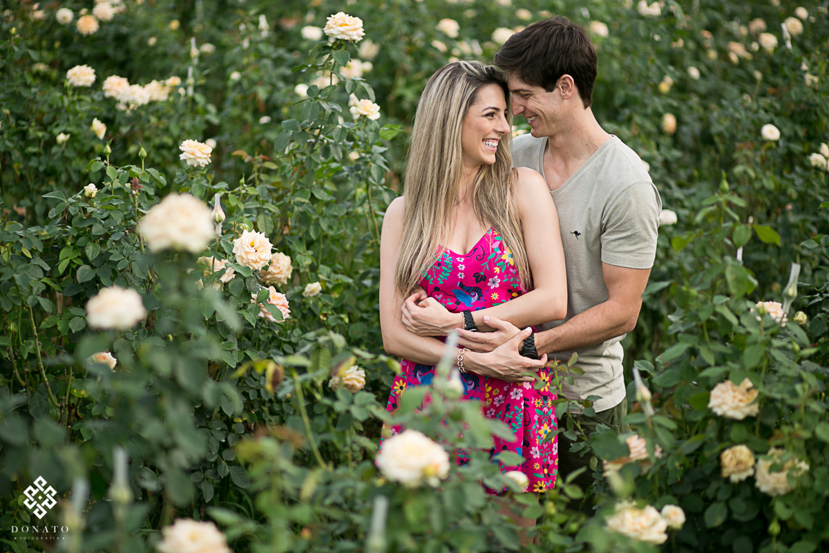 Noivos sao fotografados entre rosas na cor champanhe.