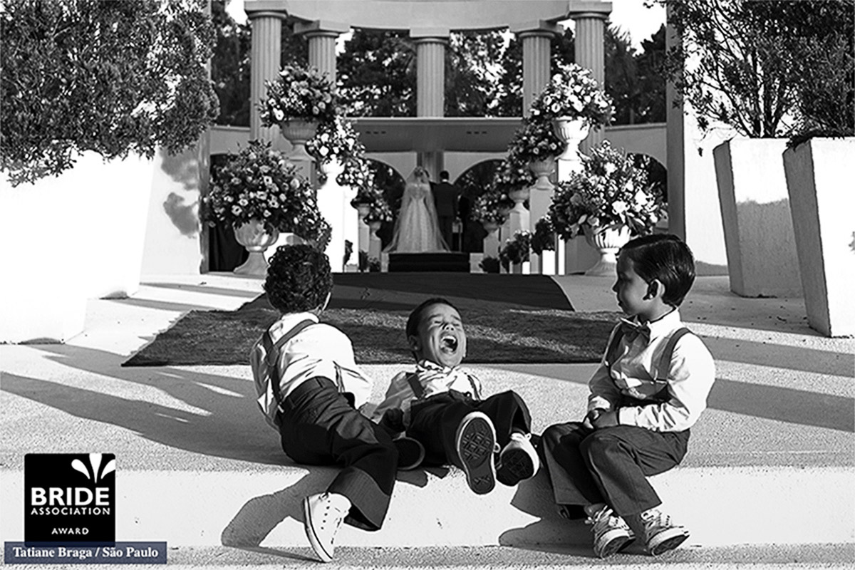 Fotos das crianças se divertindo ao fundo da cerimonia, um lindo sorriso do menino que esta ente outros dois garotos faz com que esta imagem seja forte e alegre, a foto foi premiada mais de 4 vezes.