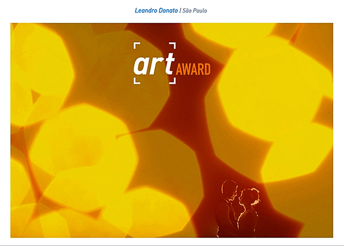 Foto de um casal entre luzes laranjas, uma linha leva o olhar do espectador até os noivos, que estam em silhueta, a foto foi premiada na Fine Art.