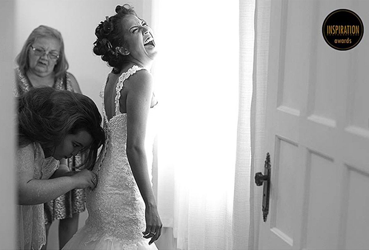 Noiva solta um lindo soffriso enguato a irmã aperta seu vestido com força, a luz é incrivel e suave, a foto ganhou alguns prêmios na categoria casamento.