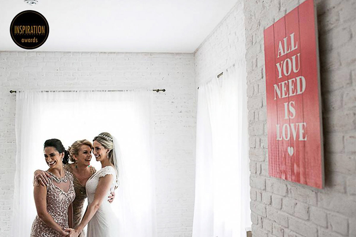 Momento unico da noiva com a mae e irmã, na composição tem uma placa dizendo All Need is Love.