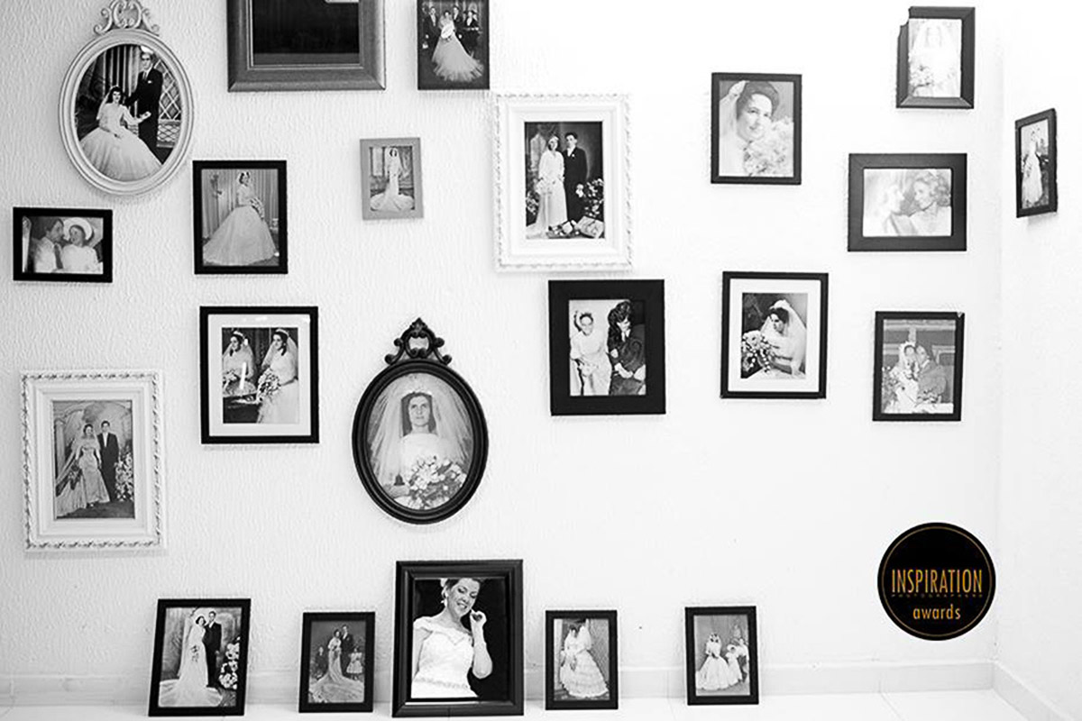 Noiva é fotografada entre varios porta retratos, refletida em um espelho, a imagem faz parecer que a noiva é uma imagem de um outro porta retrato, premiada duas vezes.