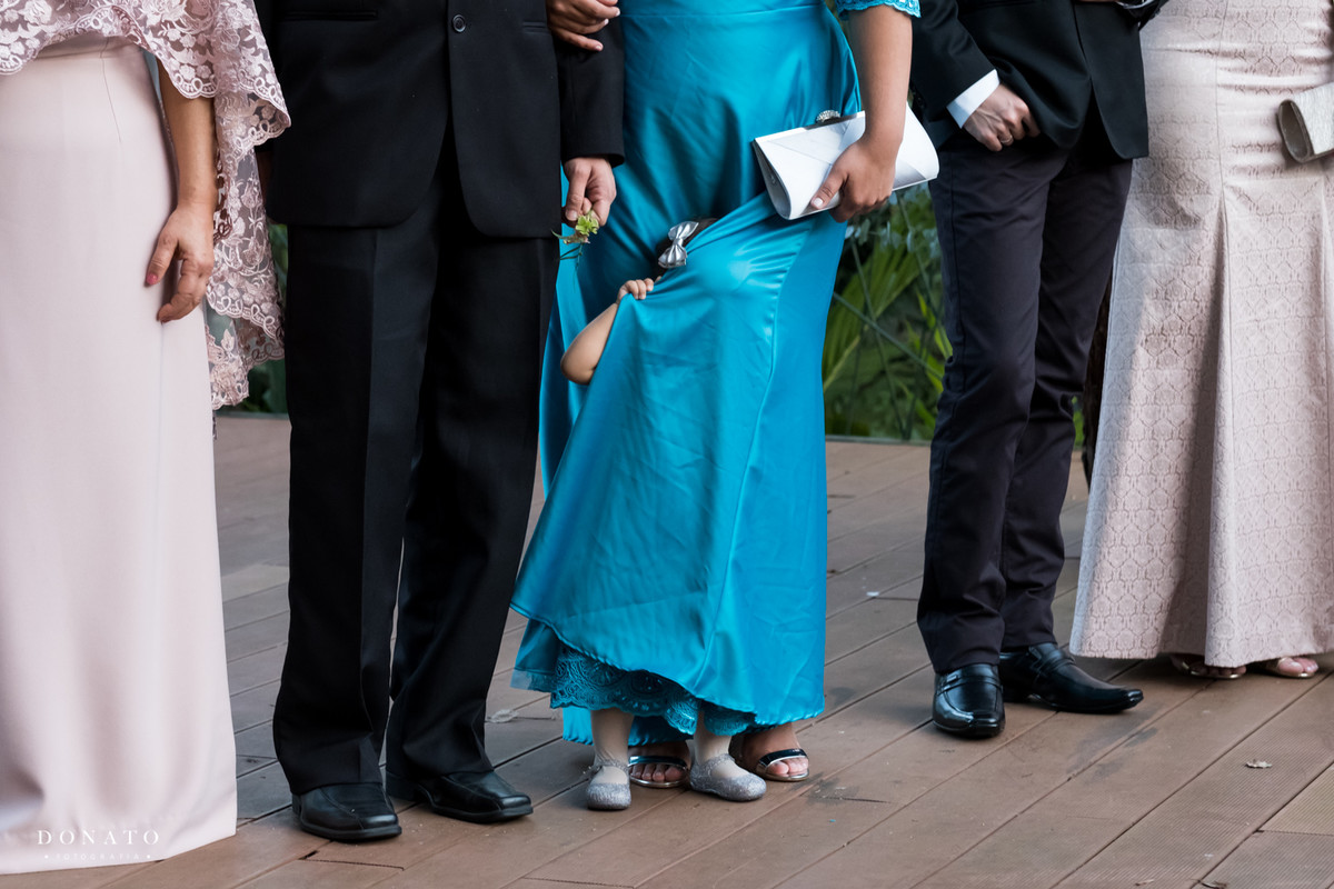 Daminha se esconde do fotografo no vestido da mãe.