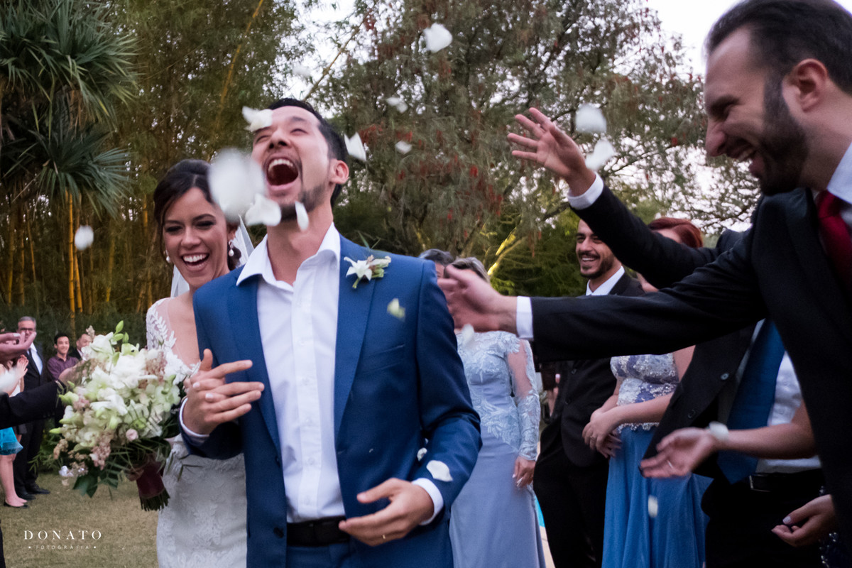 Chuva de pétalas para os noivos que se divertem com a situação