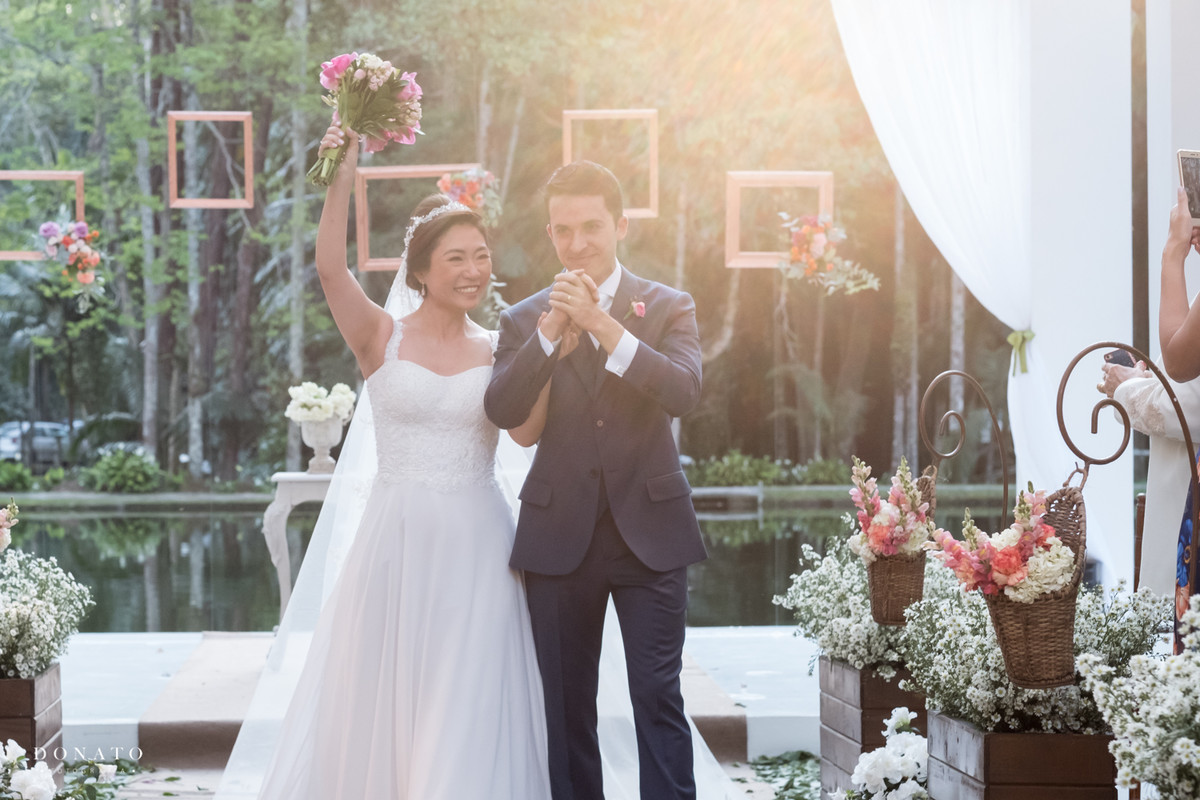 noivos saem da cerimonia realizada na fazenda, com um lindo por do sol atrás.