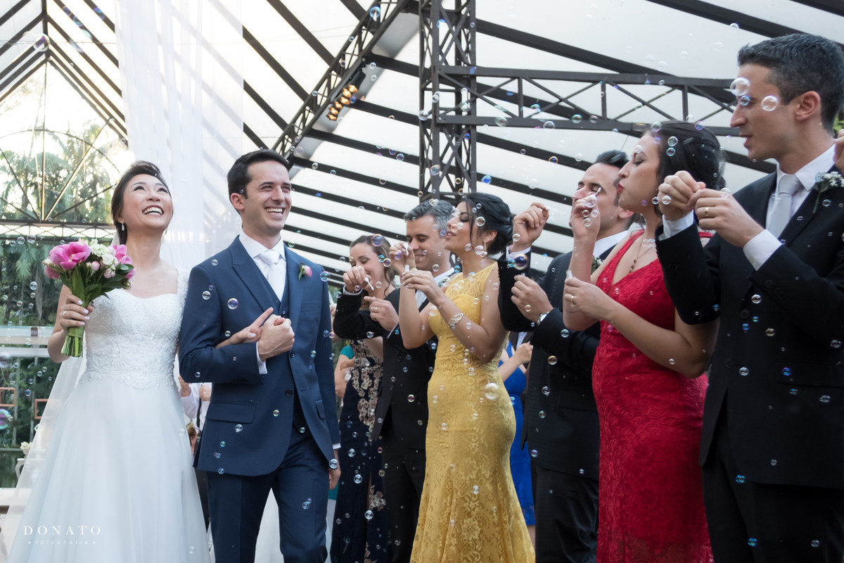 padrinhos soltam bolinhas de sabão na saída dos noivos.