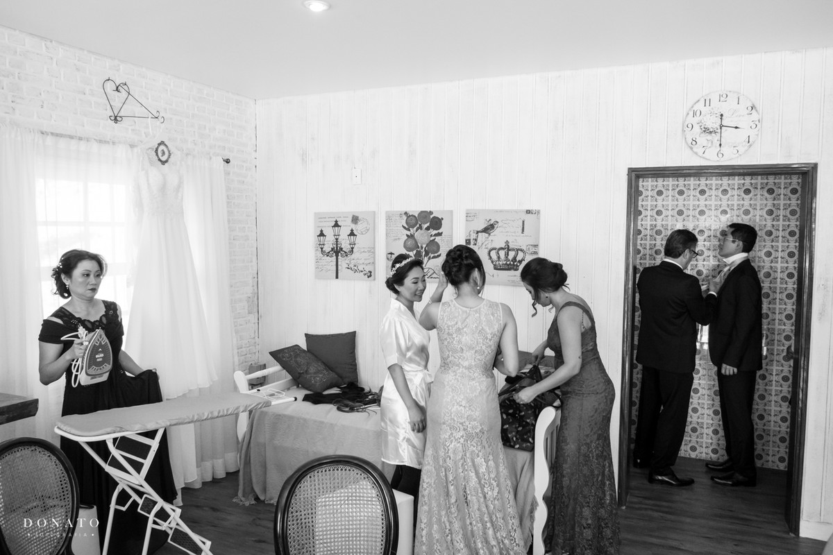 Noiva e madrinhas conversam no chalé da fazenda 7 lagoas, enquanto a madrinha passa a camisa do noivo.