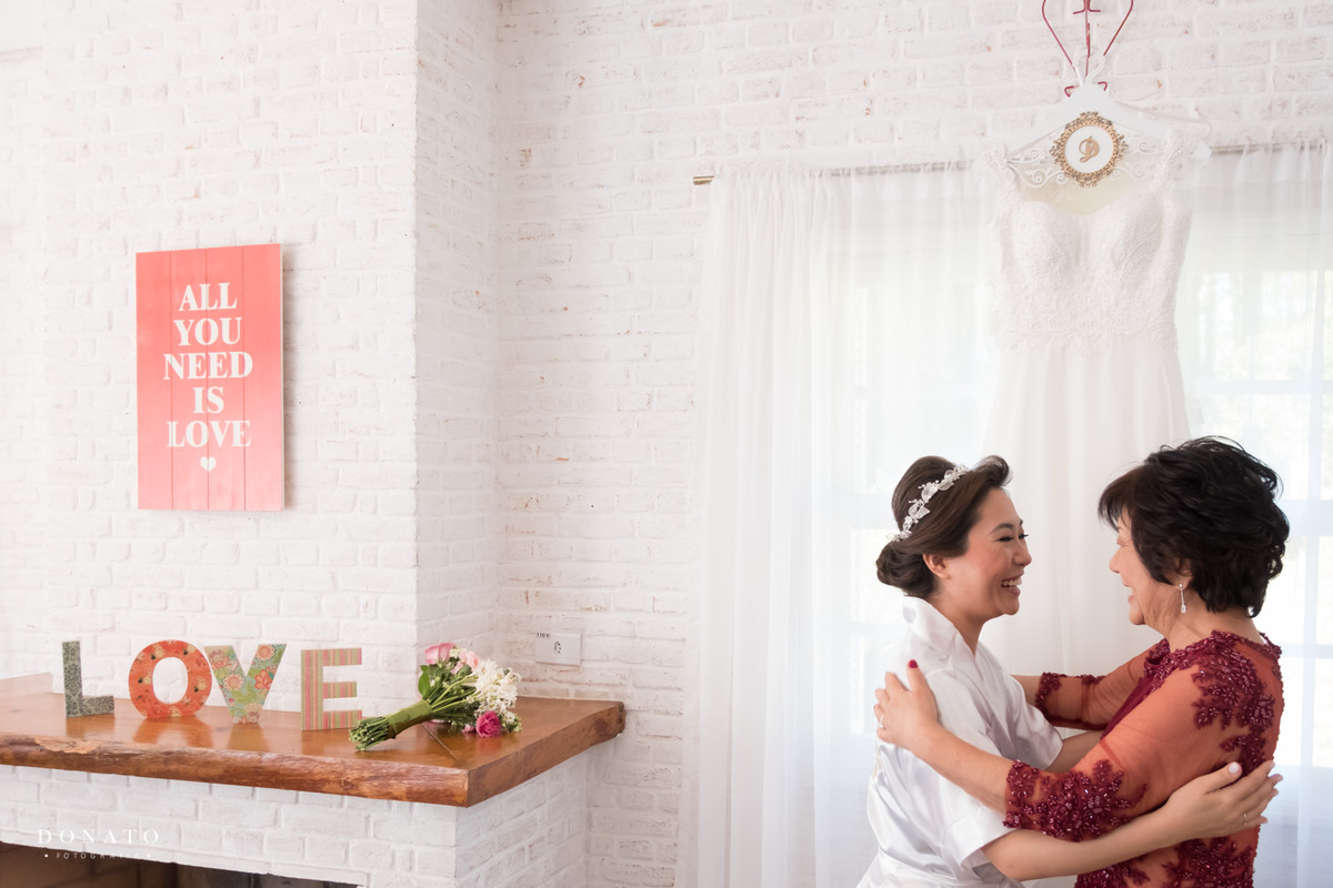 noiva e mãe se abraçam em frente do vestido na fazenda 7 lagoas.