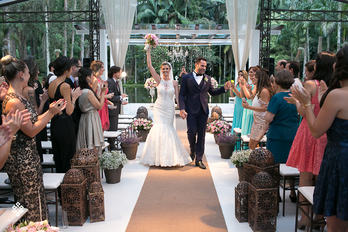 noivos saem alegres com braços erguidos em comemoração do sucesso do casamento.