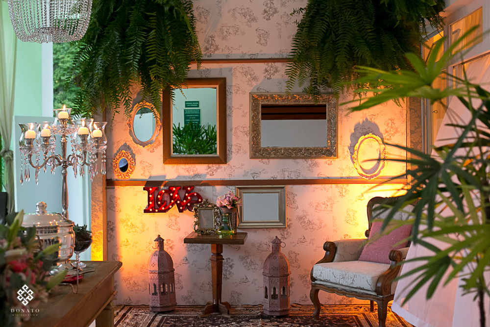 detalhes em quadros e espelhos na parede, samambaias fazem parte da decoração penduradas no teto.