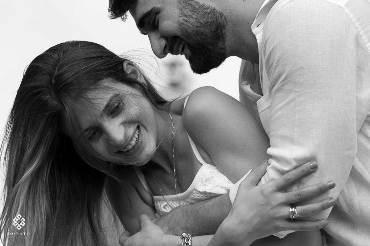 Noivo beija a nuca da noiva enquanto ela tenta fugir, muito bonita esta foto.