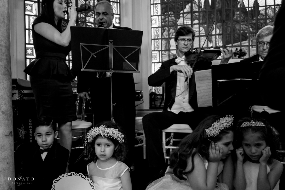 Daminha tampam os ouvidos com o som alto da musica da cerimonia.