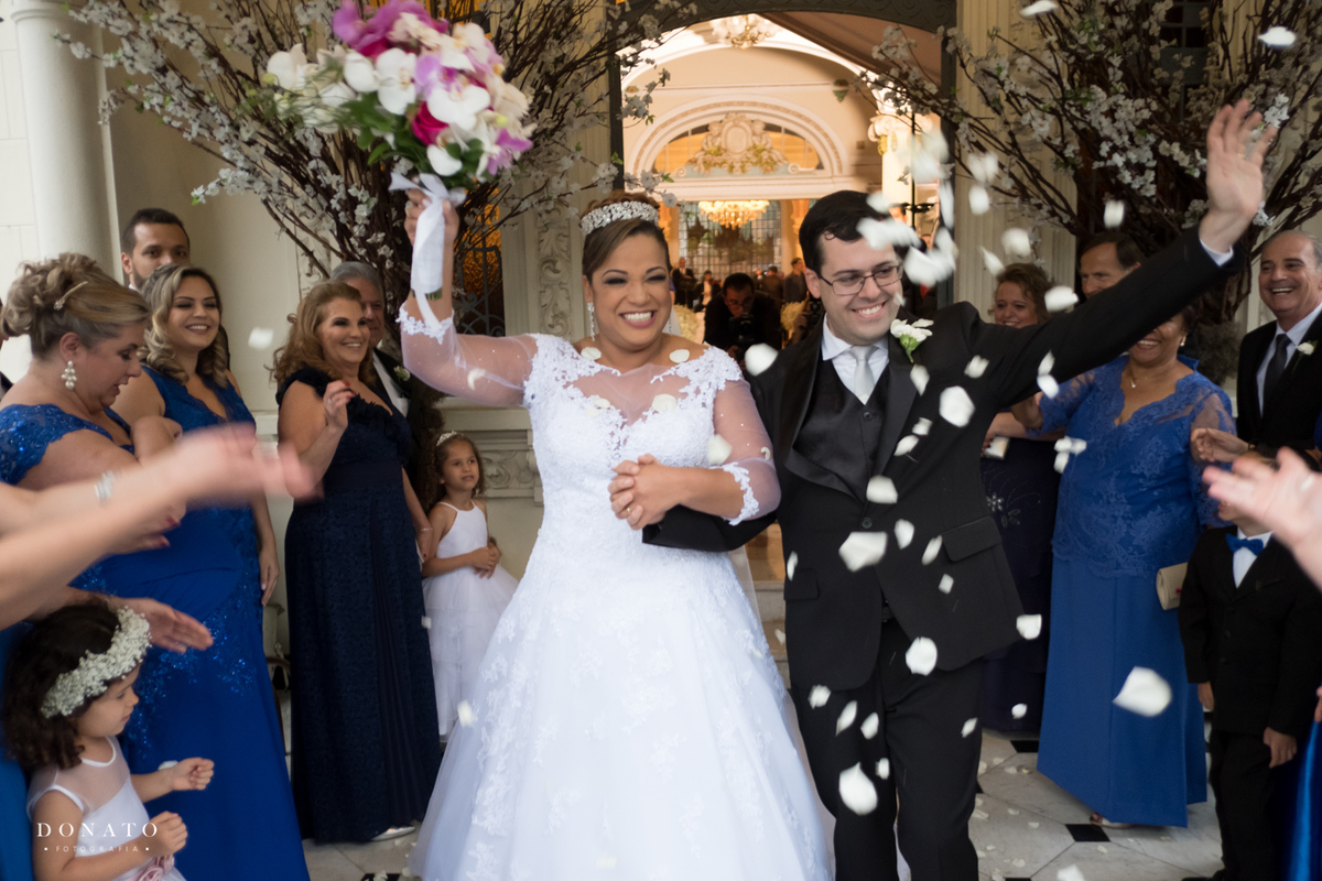 noivos saem felizes da cerimonia com uma linda chuva de pétalas.