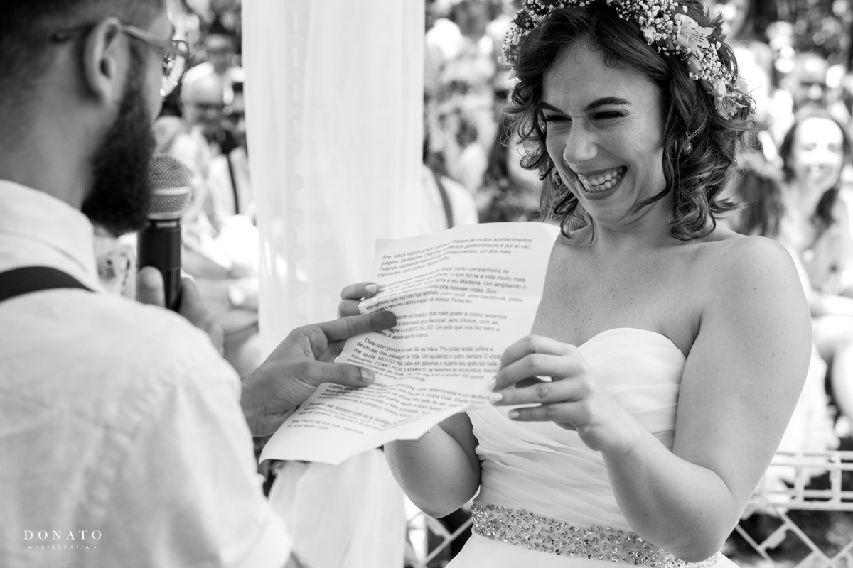 Noiva da uma linda risada ao ver o texto do noivo na hora dos votos.