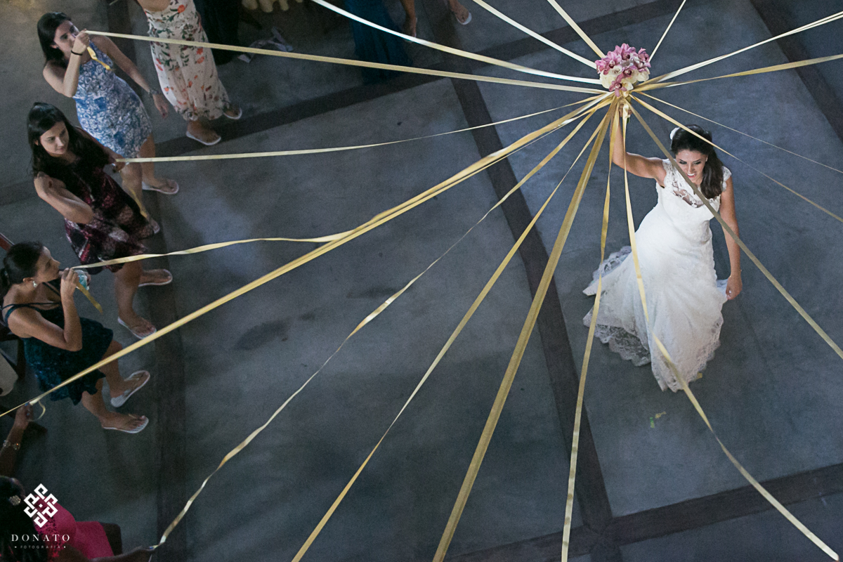 Noiva faz roda e amarra o bouquet com fitas, as convidadas pegam a fita para ver que vai ficar com o bouquet.
