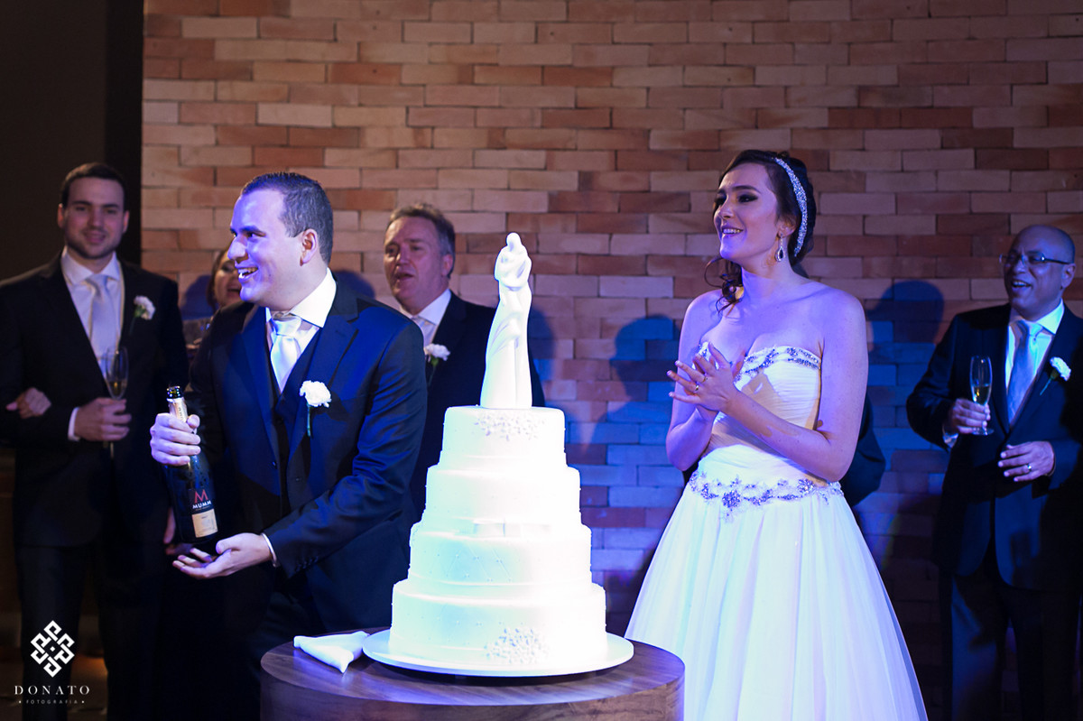 noivo estoura a champanhe, a noiva sorri e comemora junto o momento único.