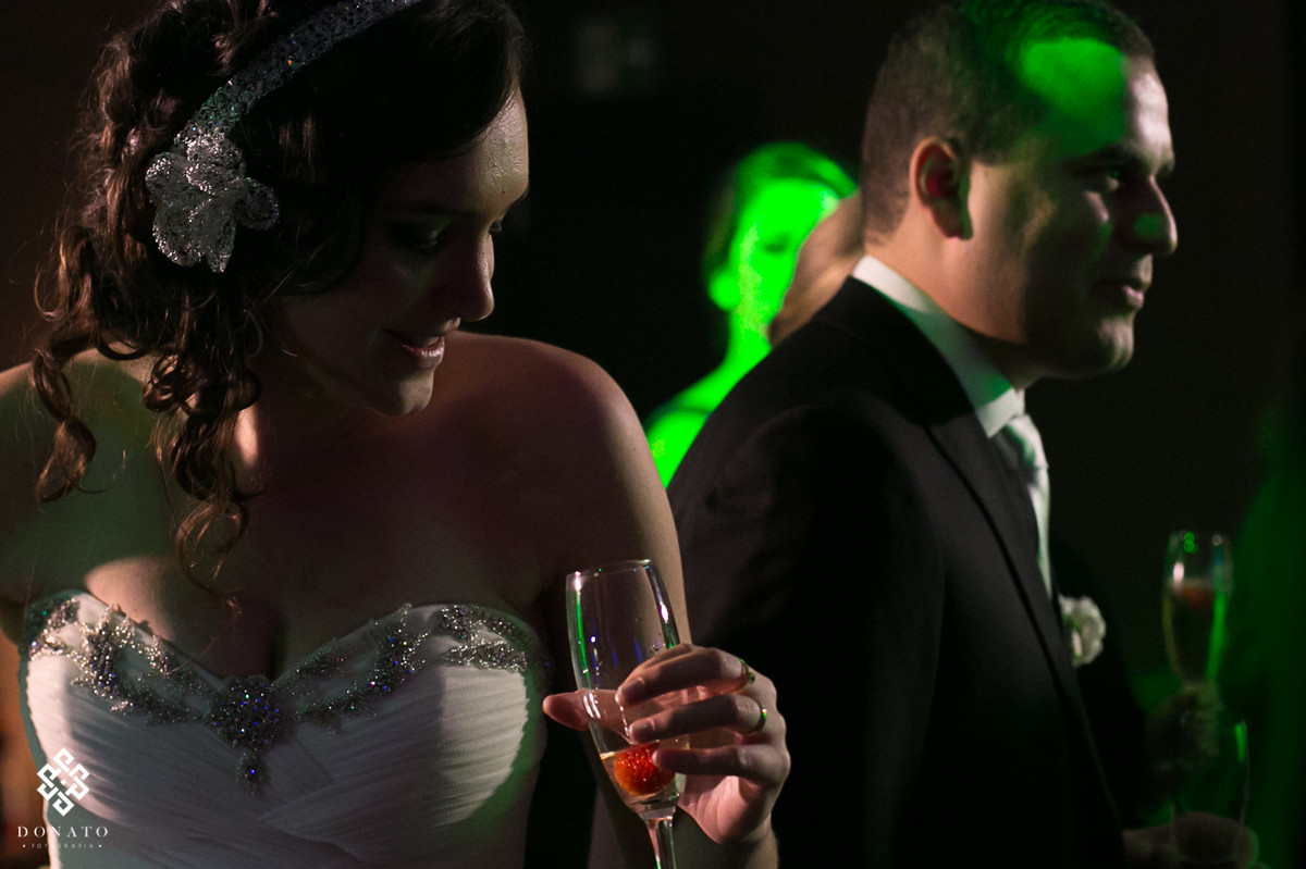 noiva dança com taça na mão, com uma luz de recorte incrivel, deixando tudo ainda mais bonito.