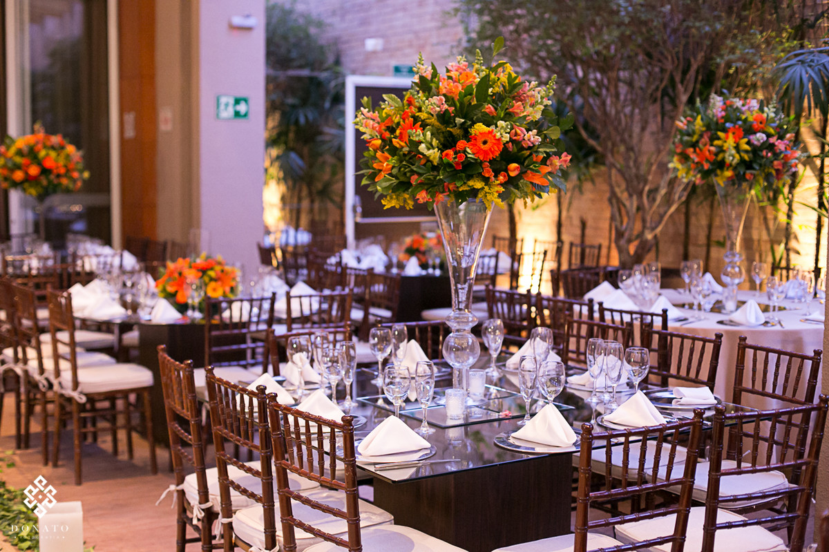 Visao geral do salao de festas do villa bisutti 011, com arranjo alto com flores amarelas e laranja.