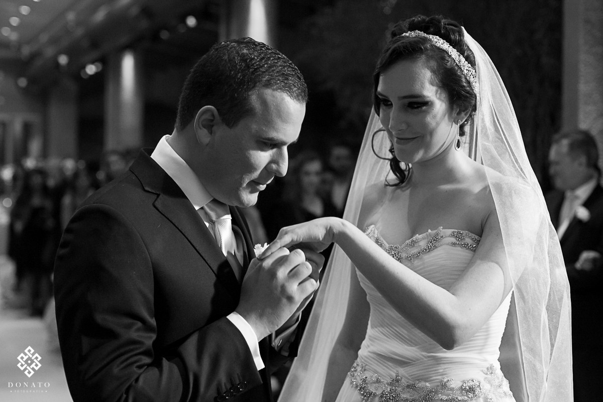 noivo beija a mão da noiva, o lindo sorriso da noiva mostra o quanto o casal se ama.