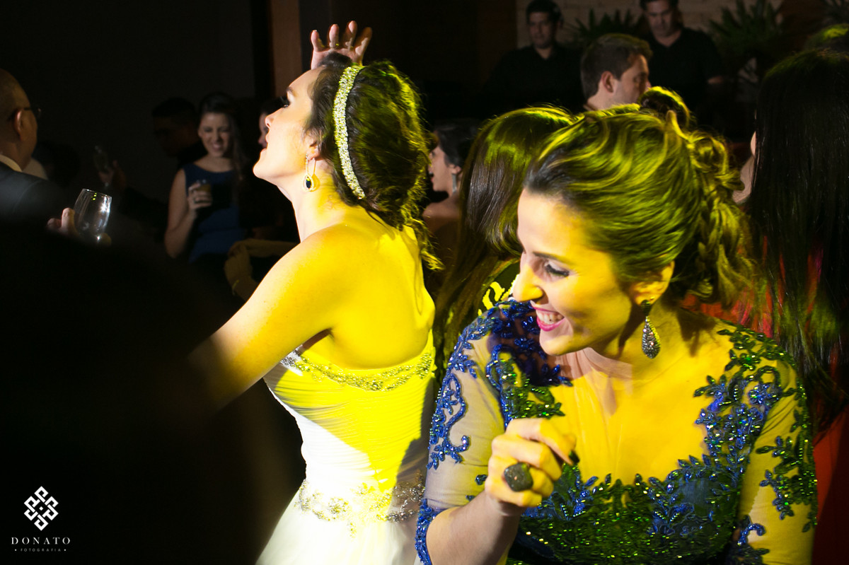 noiva e madrinhas se divertem, estao dançando com uma luz amarela muito legal.