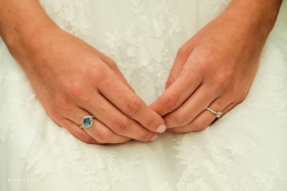 Detalhes da mão da noiva com anel de esmeraldas.