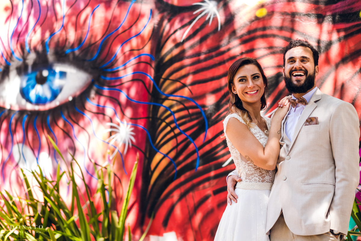 Foto dos noivos com grafite muito colorido.