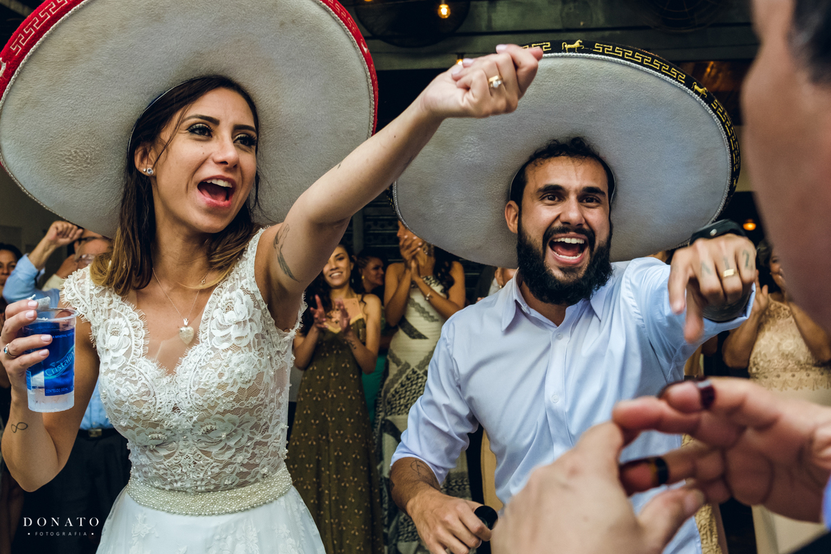 Noivos com chapéu se divertem com os Mariachis.
