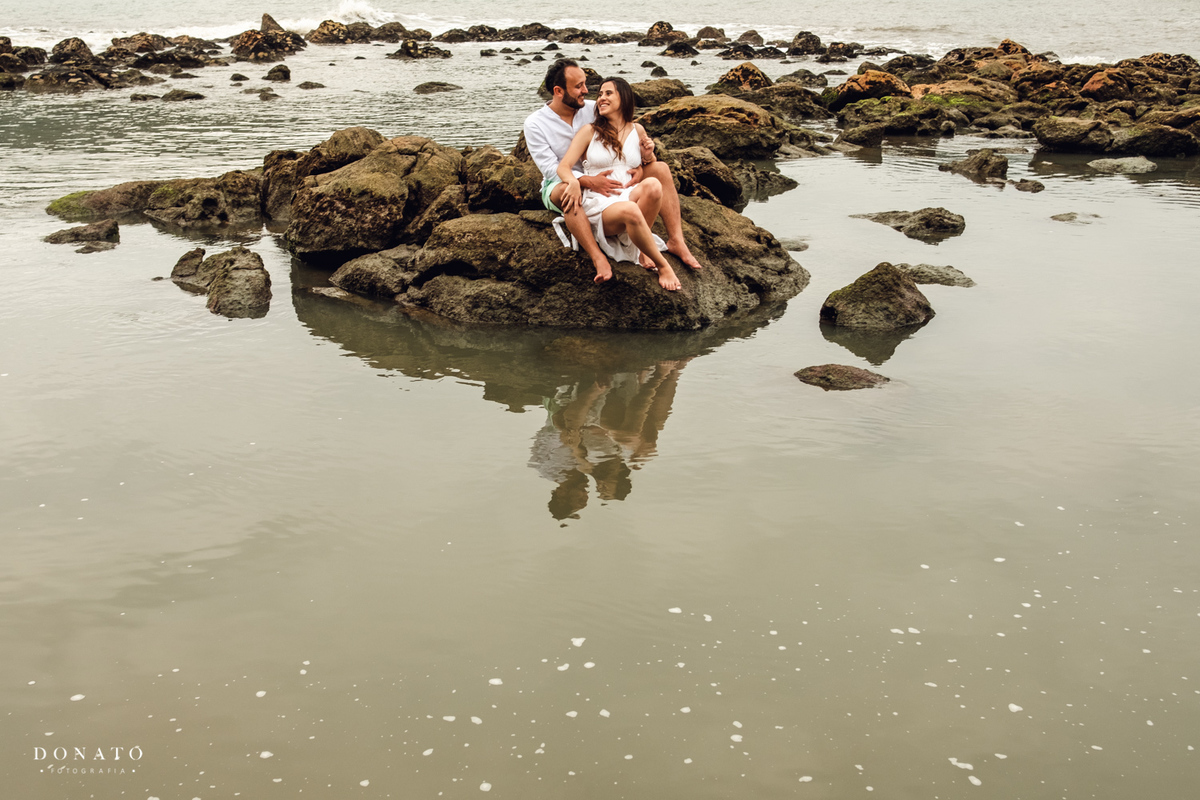 noivos sentados na ilha de pedras da praia das conchas SP.