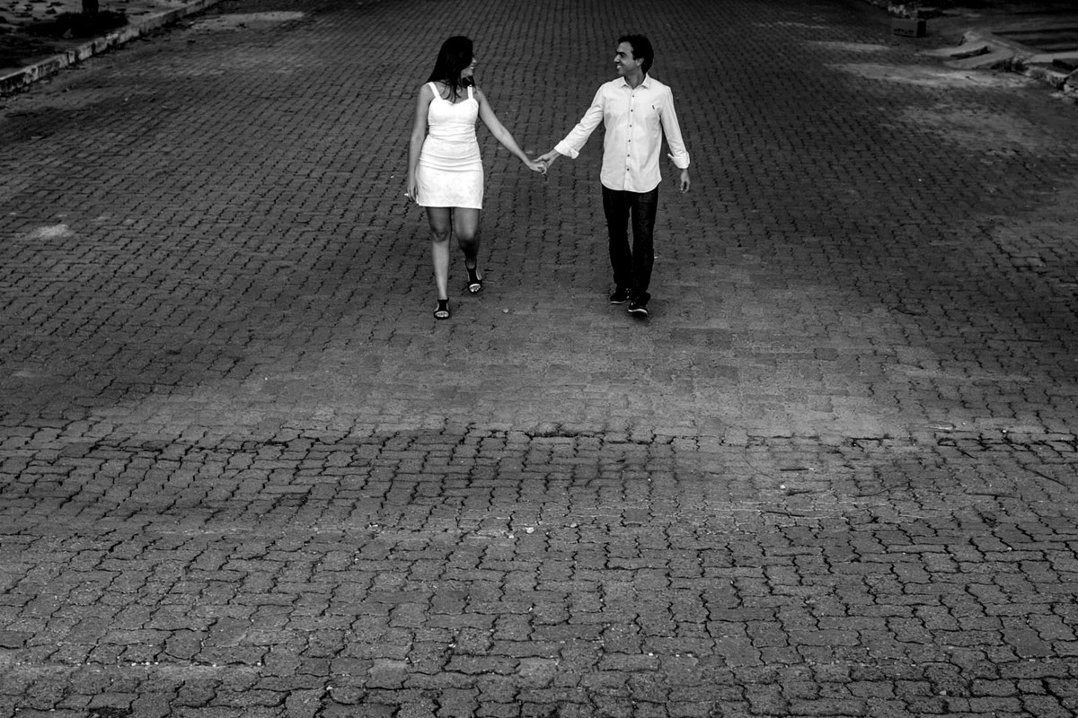 Casal passeia de mãos dadas, sobre rua de pedras, aqui a foto foi feita de cima onde pode limpar a cena como um todo, muito agradável de se ver a foto.