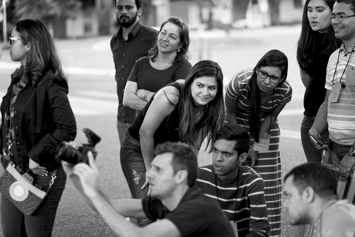 Leandro clica casal, mostrando a pratica aos alunos que ao fundo olham como fotografar em um angulo diferente.