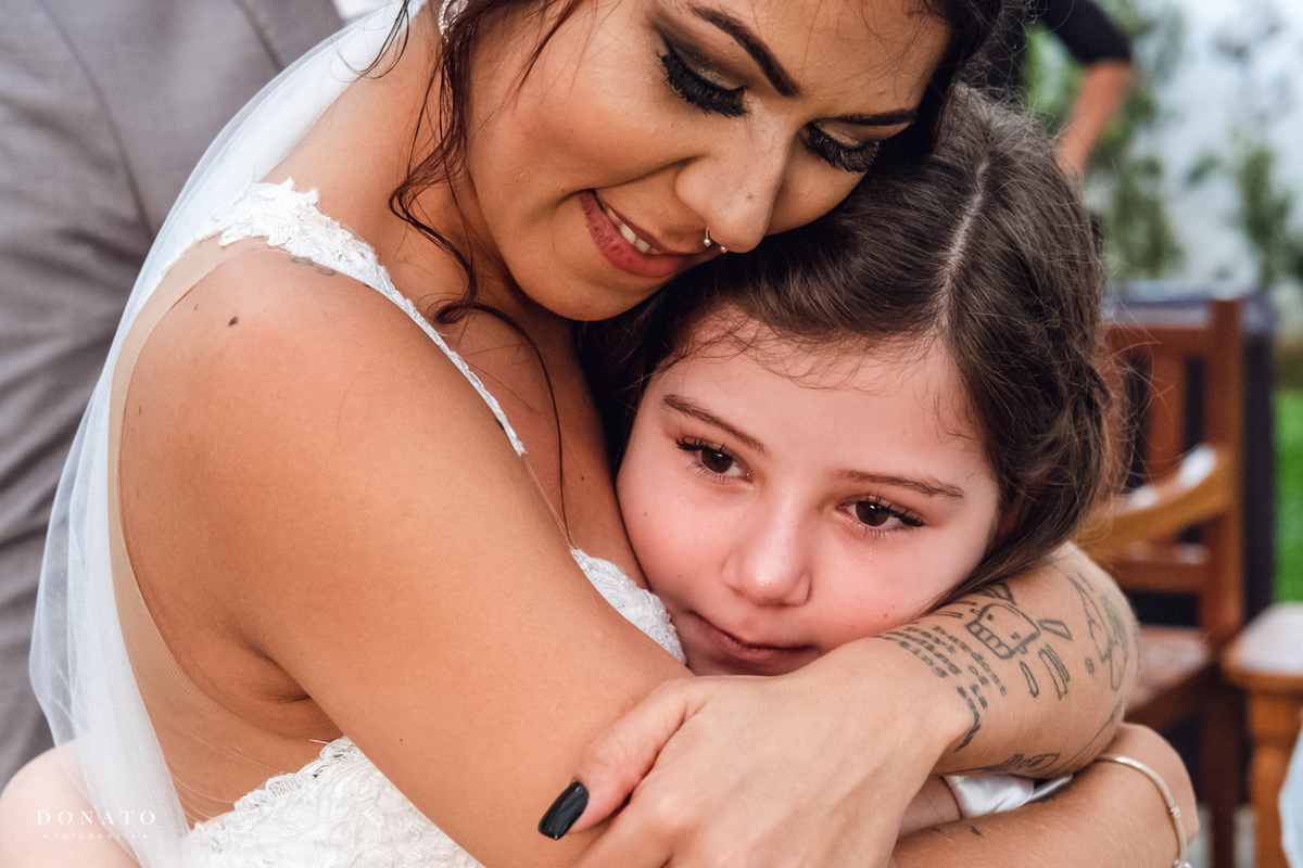 Noiva abraça a filha do noivo.