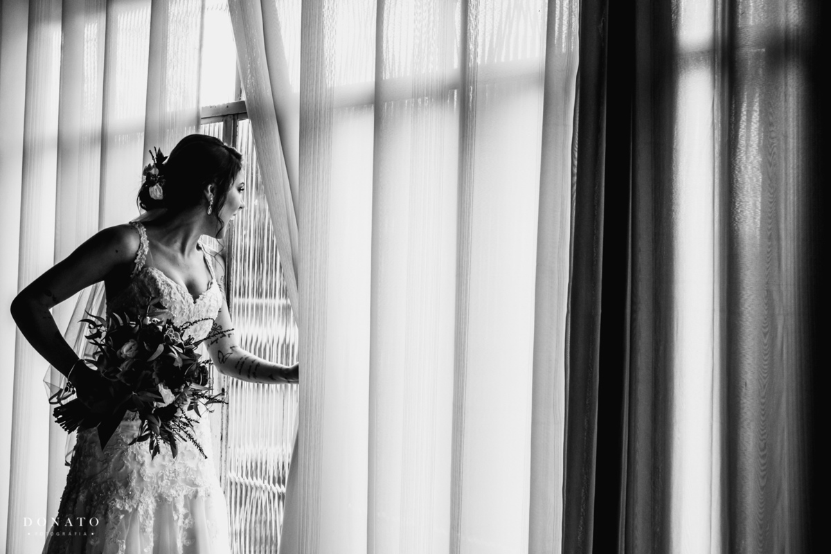 Noiva espia pela janela a cerimonia acontecendo a noite.
