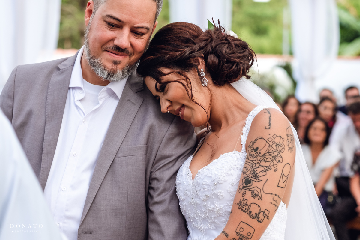 Noiva se encosta no noivo na cerimonia.