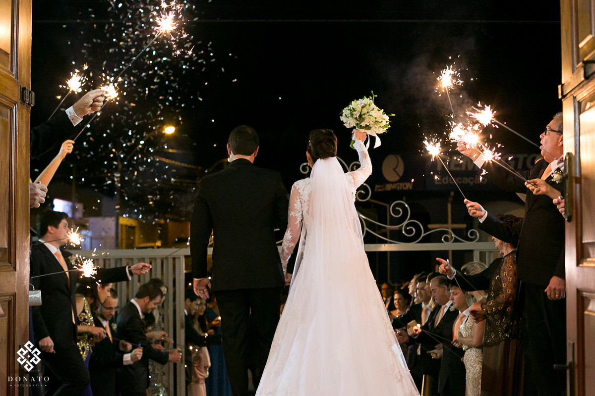 Saida emocionante dos noivos na igreja, padrinhos acendem bastoes com fogo iluminando e fazendo deste momento algo ainda mais unico.