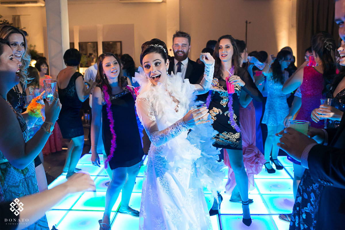 Noiva dançando com amigos, sobre uma pista de led azul, momento perfeito.