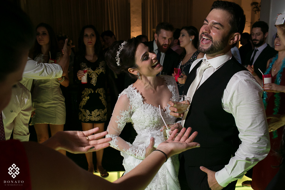 Noivo solta um grito na pista de dança, a noiva ao lado canta alguma musica muito divertida.