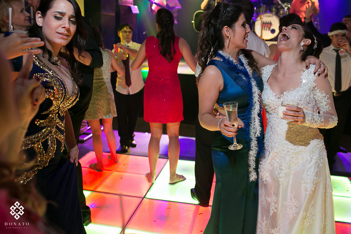 noiva e amiga se abraçam ao meio da pista de dança.