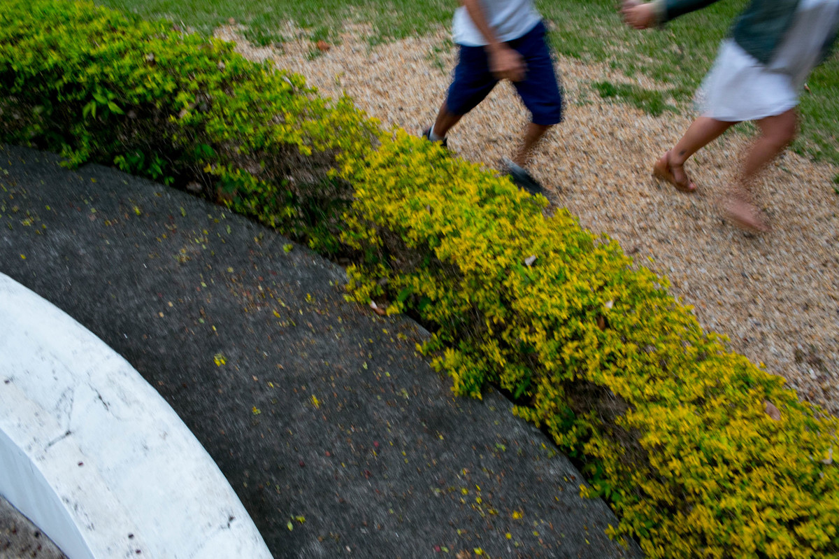 foto do detalhe das pernas em movimento, a foto tem um angulo diagonal, que deixa a foto muito equilibrada, alem da textura das pedras, do verde da grama e do cinza do asfalto.