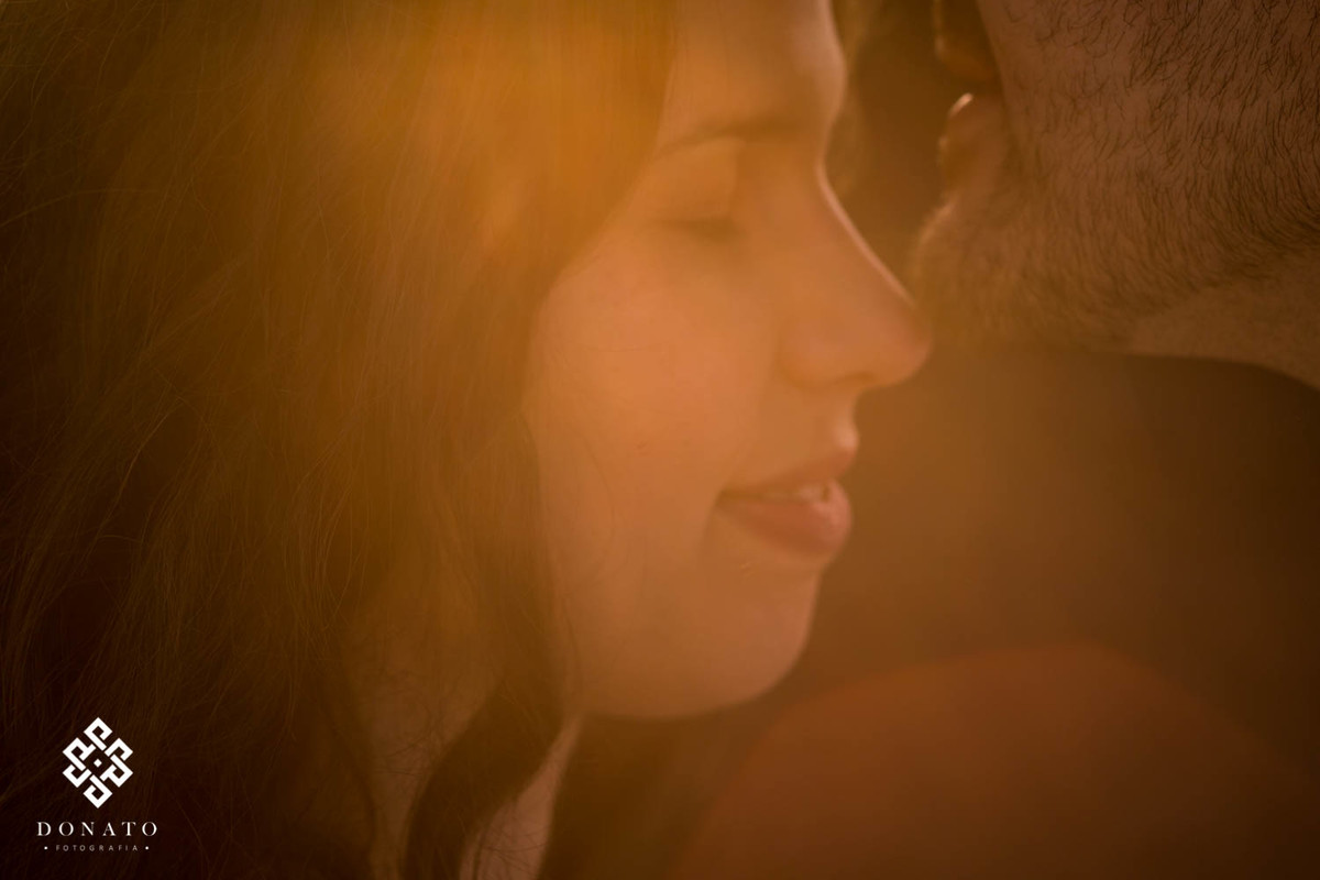 Noivos se encostam com os rostos, enquanto um luz dourada entra na imagem.