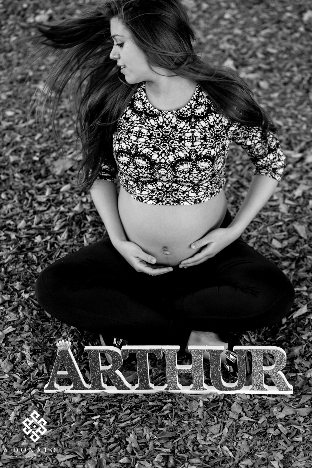 Foto da gestante feita sobre folhas caidas, o cabelo se movimenta ao vento.