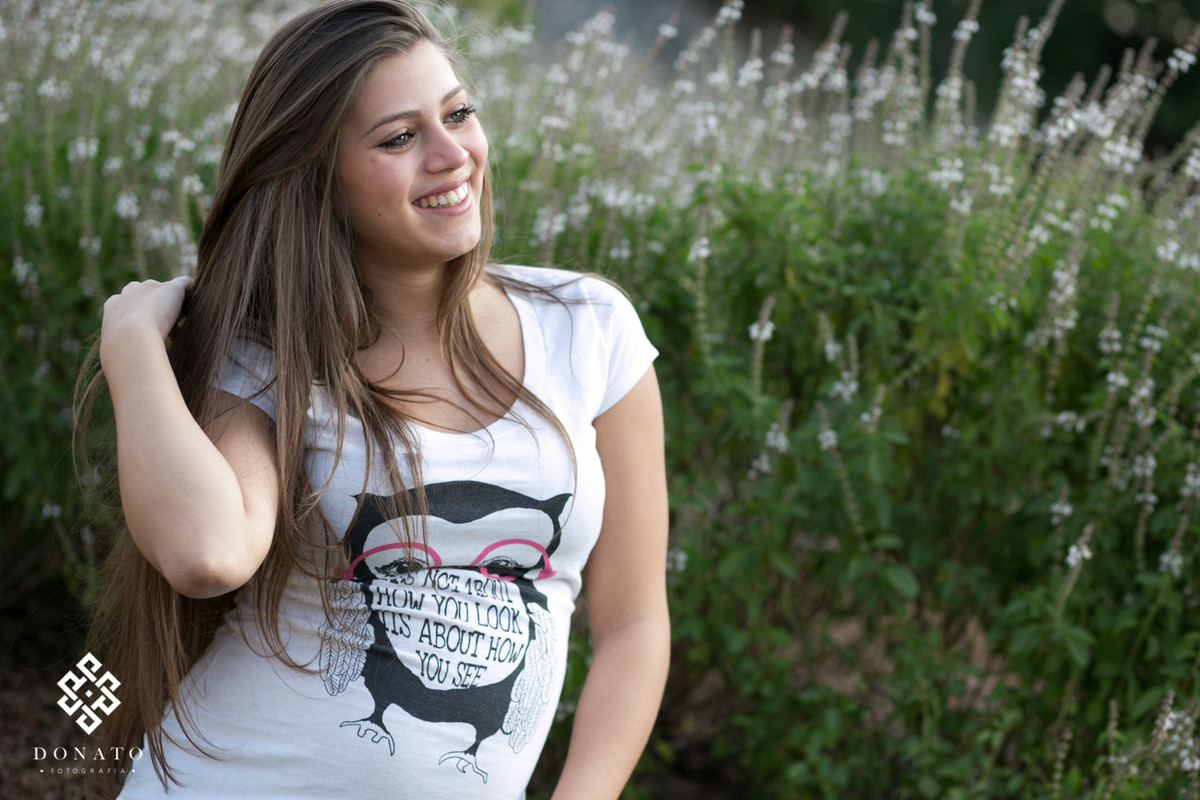 foto da gestante ao fundo fores pequeninas e branquinhas.