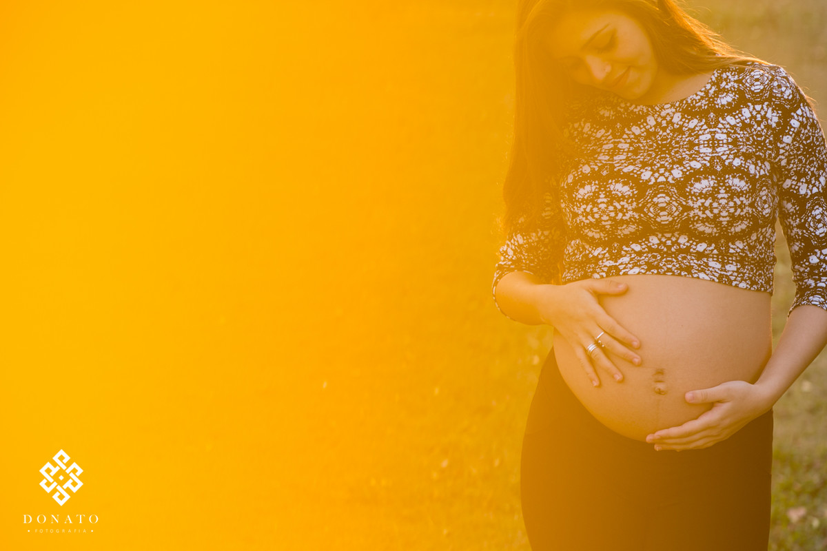 retrato alaranjado da leticia, com as maos na barriga.