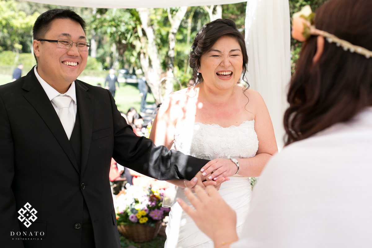 Noivos dão risadas durante a cerimonia realizada no espaço natureza.