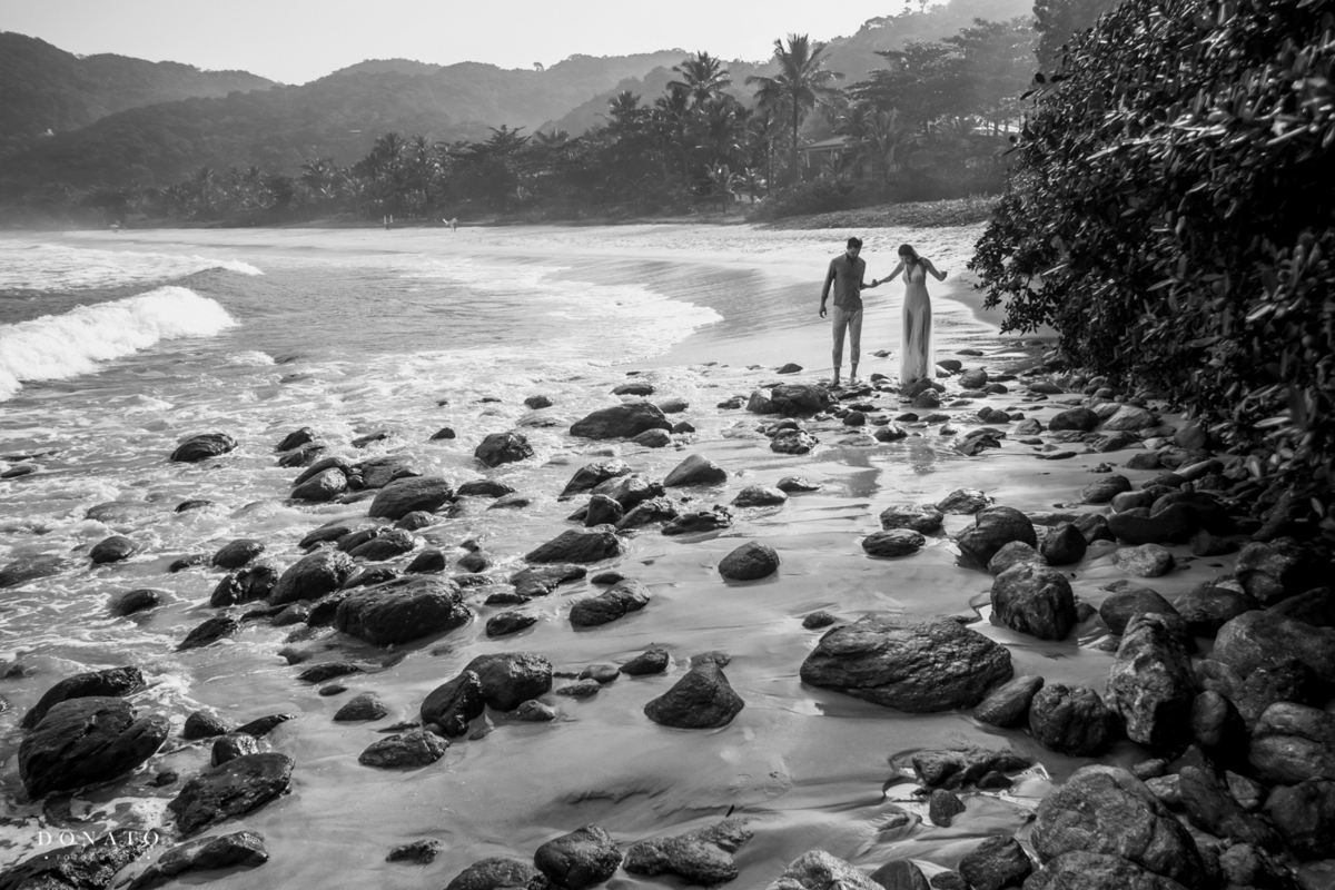 casal caminha entre pedras na praia, s.