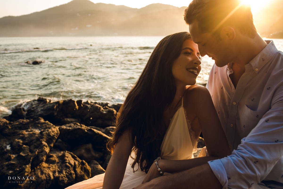 Casal namora com por do sol na praia.