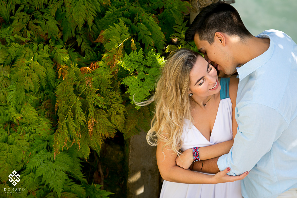 noivos namoram a beira mar, em frente a uma linda arvore.