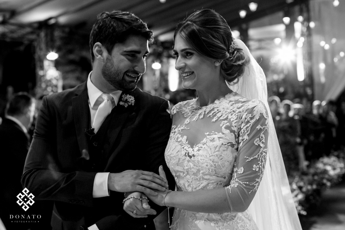 noivos dão as mão e se olham emocionados no altar.