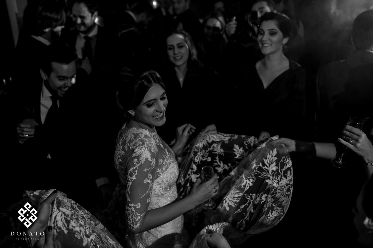 Amigas dançam com a noiva e mexem no vestido, balançando.